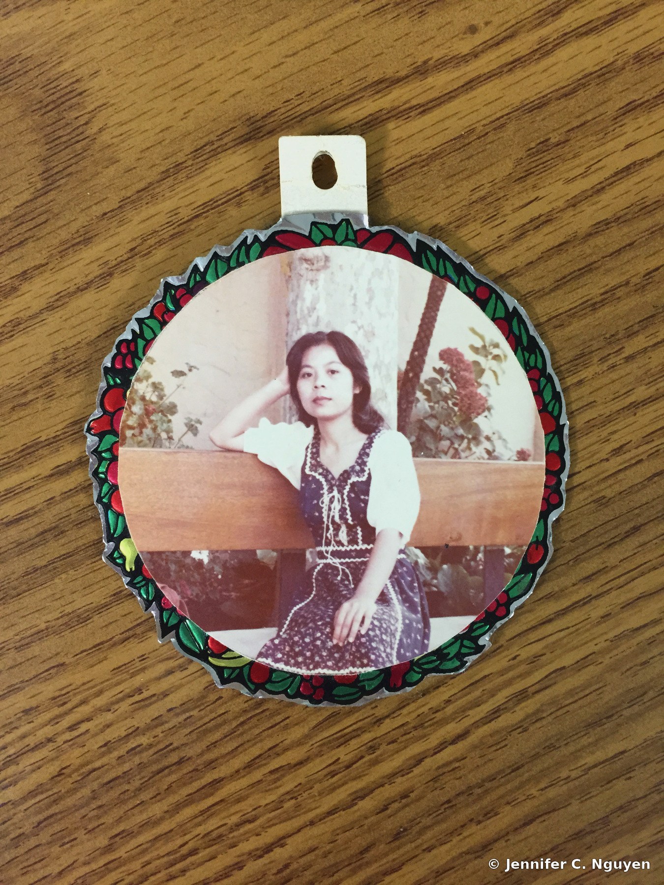 Original archival photograph of a young woman in a vintage dress, mounted inside a decorative circular photo ornament resting on a wood grain table